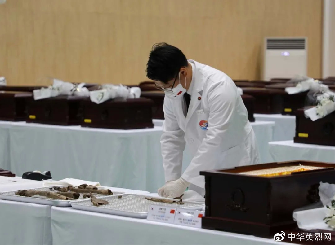 韩方工作人员将中国人民志愿军烈士遗骸包裹后放入棺椁。张悦 摄
